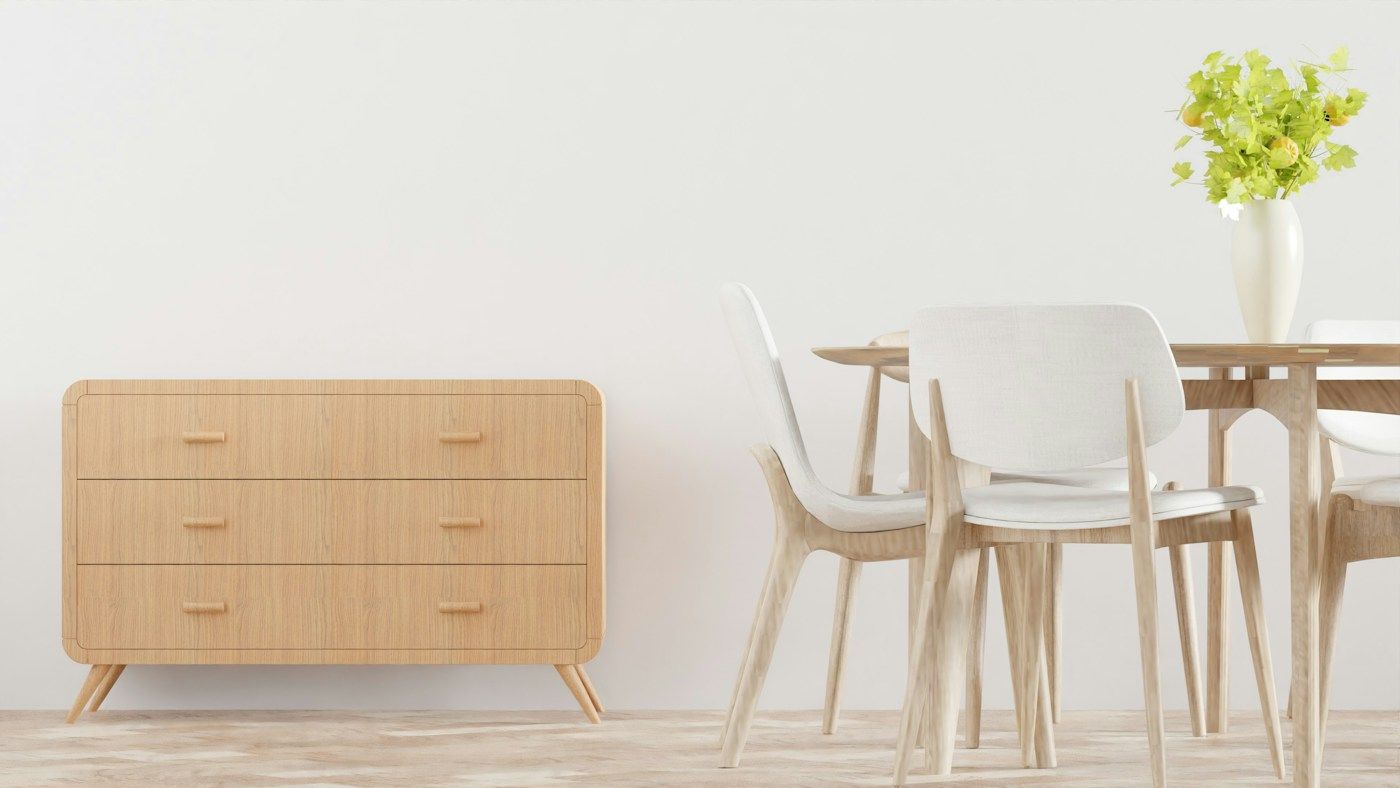 Commode et chaises neuves en bois clair dans une pièce aux murs blancs