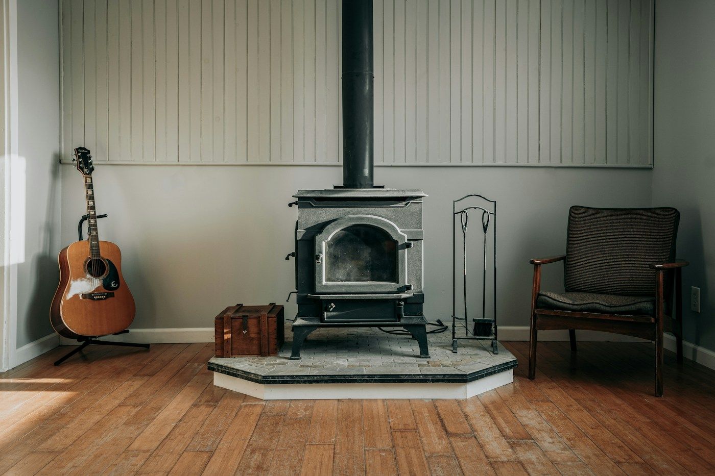 Poêle à bois en fonte installé sur un socle dans un salon au parquet clair